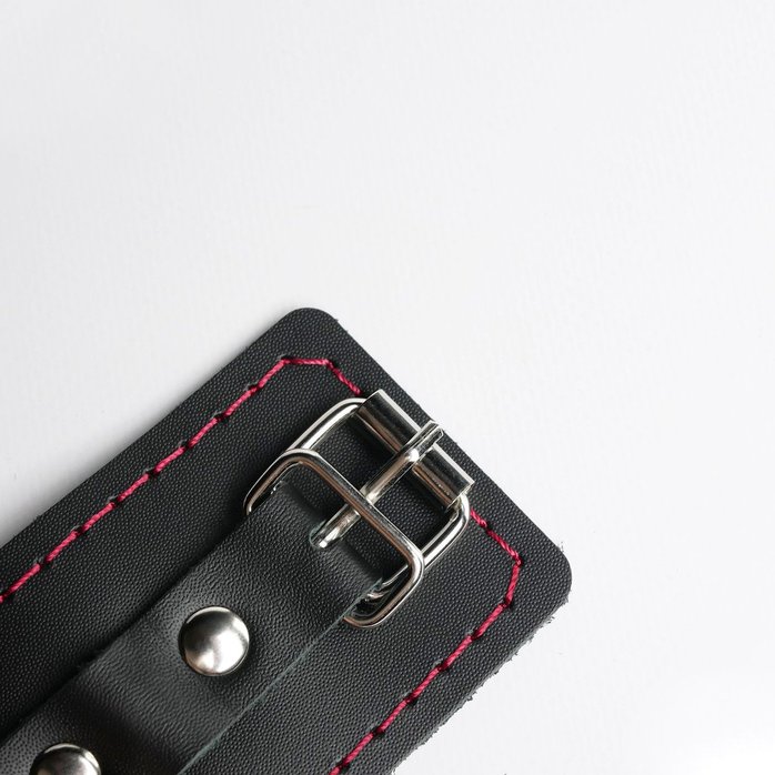 Черные кожаные наручники с красной строчкой. Фотография 3.